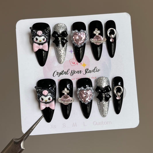 Product Features:

Theme: Kuromi
Shape: Long Stiletto
Base Colors: Minimalist Black and Silver Glitter
Embellishments: Kuromi charms, pink heart gemstones, Western Empress Dowager Diamond, black bows, Starlight Love Saturn Ball
Style: Playful, cute, and elegant
Quality: High-quality, handmade craftsmanship